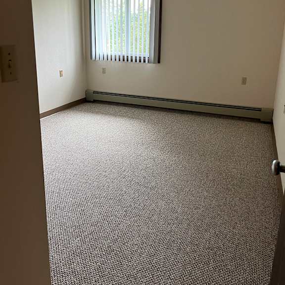 a window with blinds is on the left side of a room with a textured wall.