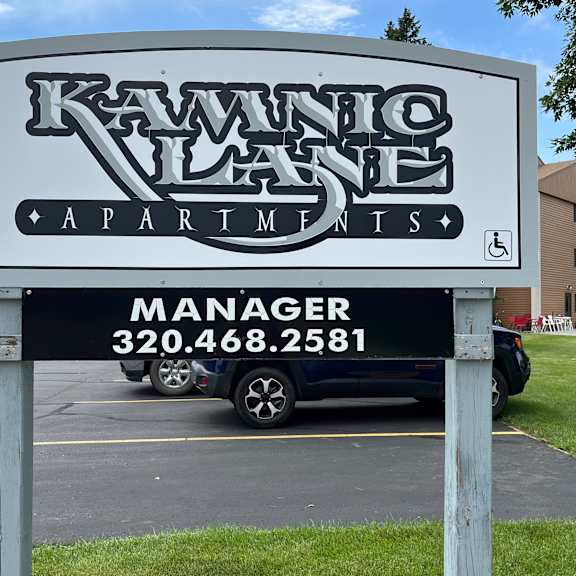 a sign for kawanico apartments with a phone number for the manager.