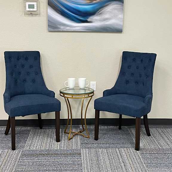 a blue chair with a gold frame is in front of a grey carpet.