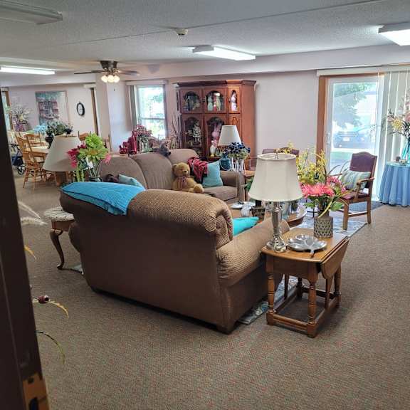 a living room with a brown couch and a table with a vase of flowers on it.