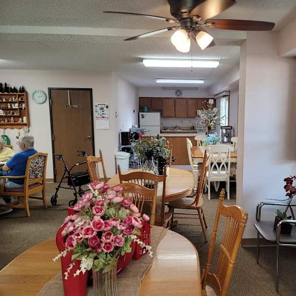 a dining room with a table and chairs and a woman sitting in a chair.