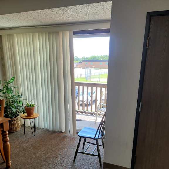 a room with a chair and a table in front of a sliding glass door.