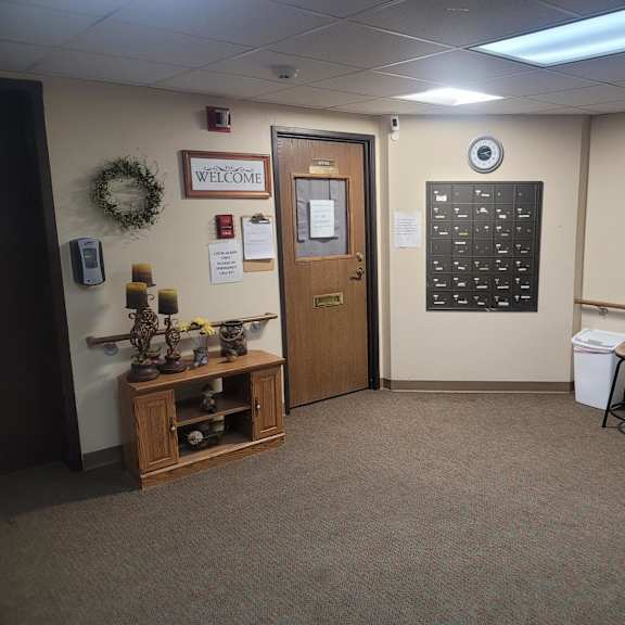 a hallway with a door, a wall clock, and a wreath on the wall.