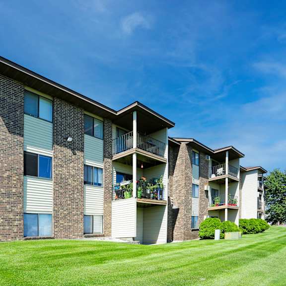 a large apartment building with a green lawn in front.