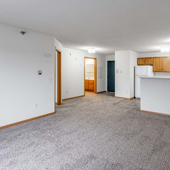 bldg a/c - a spacious living room with a carpeted floor and white walls.