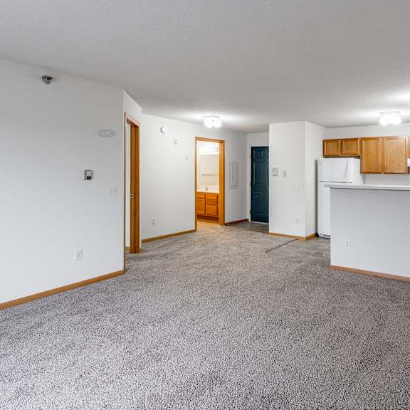 a spacious living room with a carpeted floor and white walls.