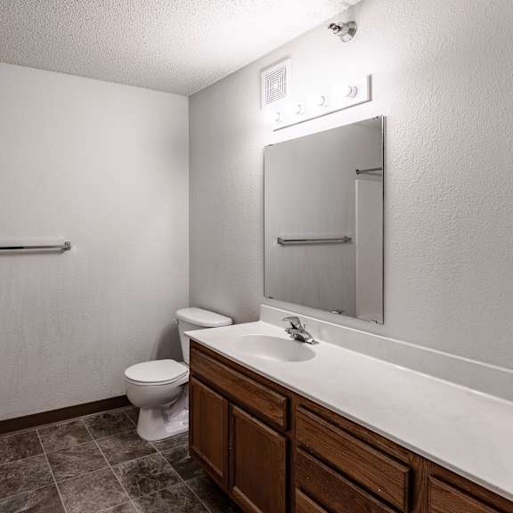 bldg a/c - a bathroom with a toilet, sink, and mirror.