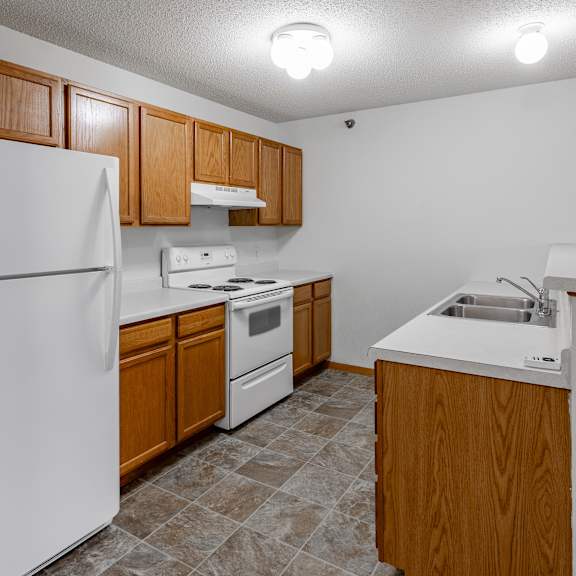 bldg a/c - a kitchen with white appliances and wooden cabinets.