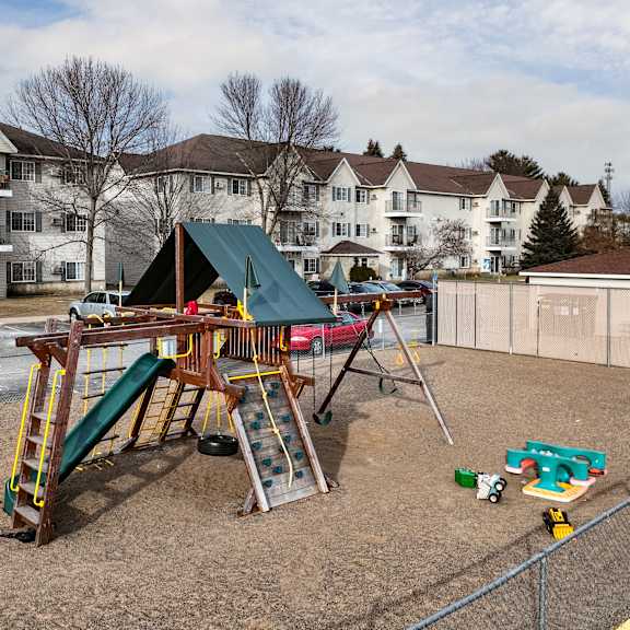 bldg a/c - a playground with a green slide and a red car.
