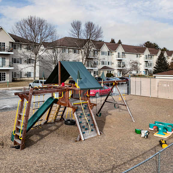a playground with a green slide and a red car.