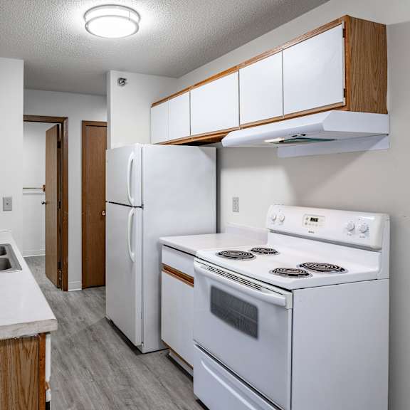 a kitchen with white appliances and wooden cabinets.