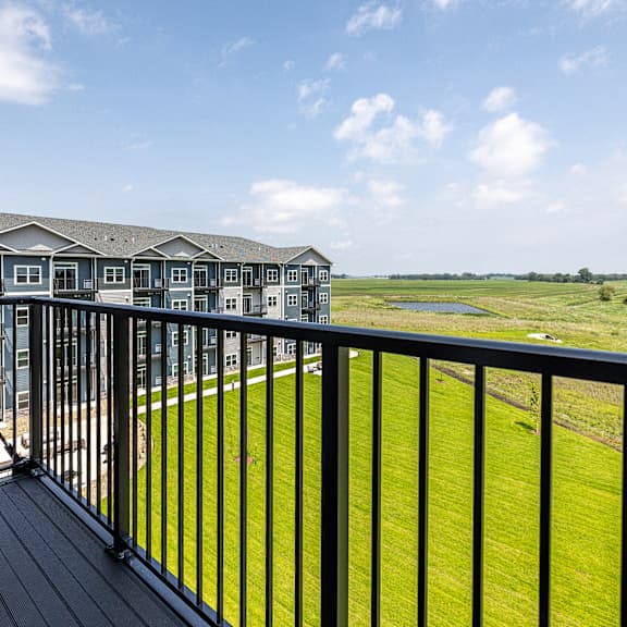 a balcony overlooks a grassy field and a building.