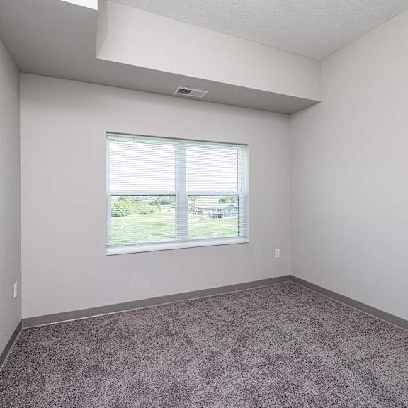 a room with a large window and carpeted floor.