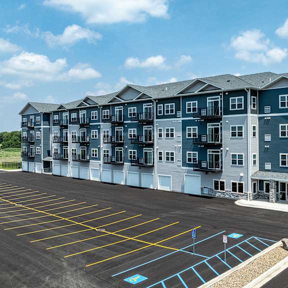 a large apartment complex with a parking lot in front.