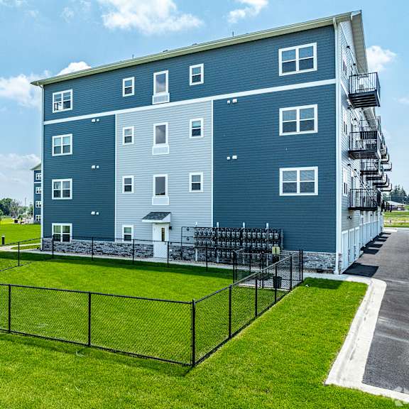 a blue and white apartment building with a black fence in front.