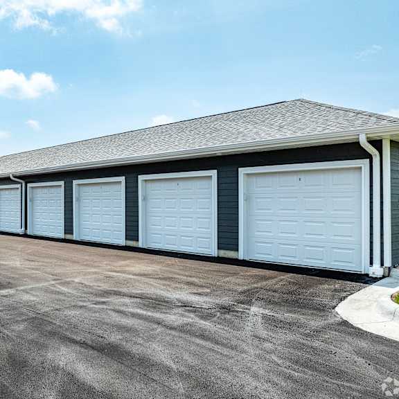 a long building with a grey roof and white garage doors.