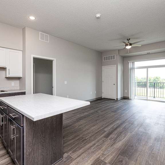 a spacious kitchen with wooden floors and a white countertop.