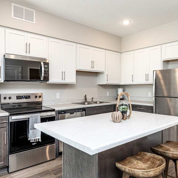 a kitchen with a white counter top and stainless steel appliances.