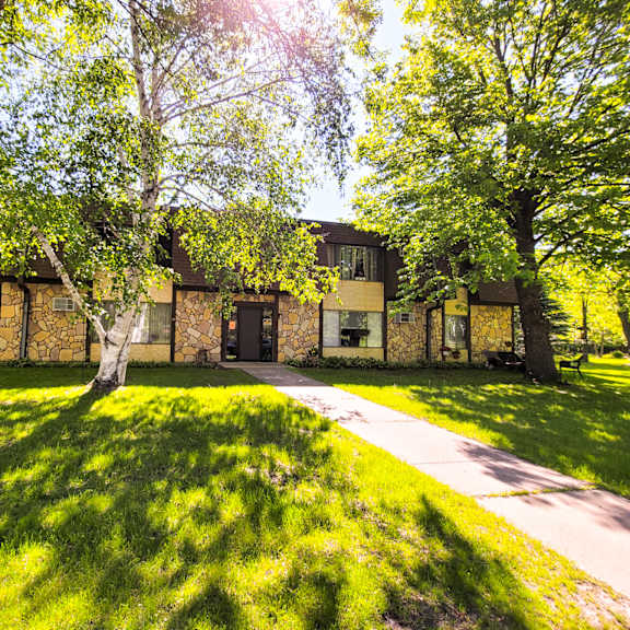 a house with a green lawn and trees in front.