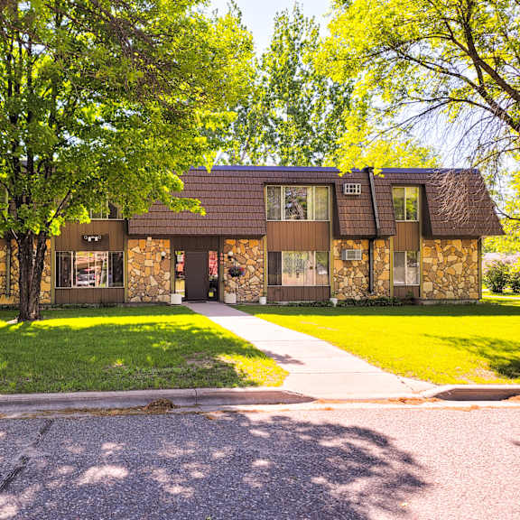 a house with a brown roof and a green lawn in front.