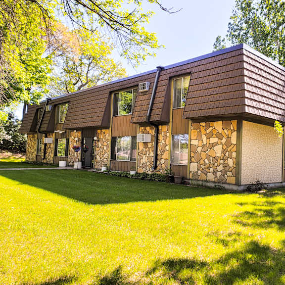 a house with a brown roof and a stone wall.