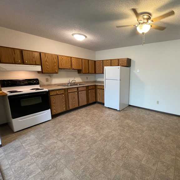 a kitchen with a white refrigerator and wooden cabinets.