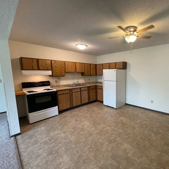 a kitchen with a white refrigerator and wooden cabinets.