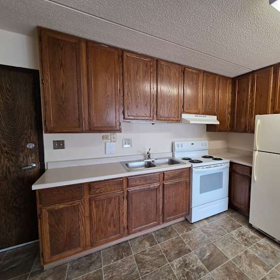 a kitchen with wooden cabinets and a white refrigerator.