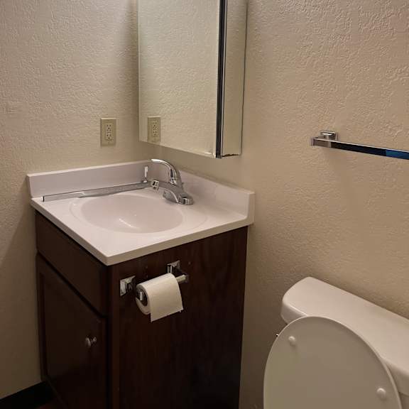 a white sink is mounted under a lighted mirror in a small bathroom.