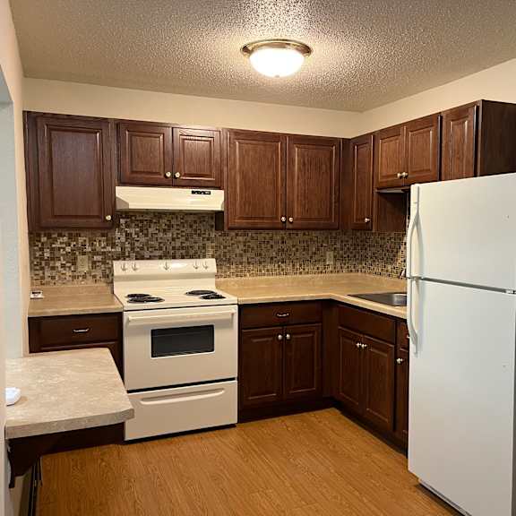 a kitchen with white appliances and brown cabinets.