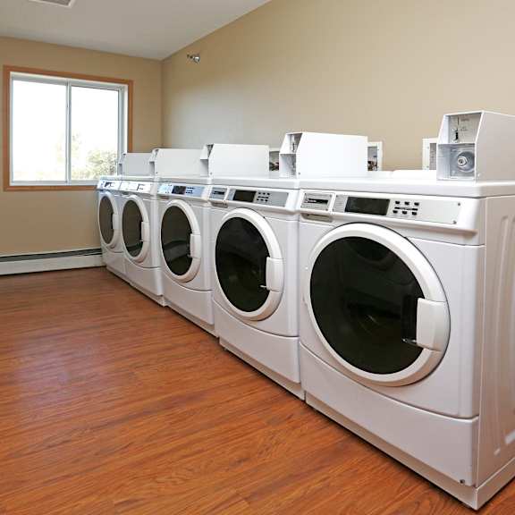 a row of white front load washing machines in a laundromat.