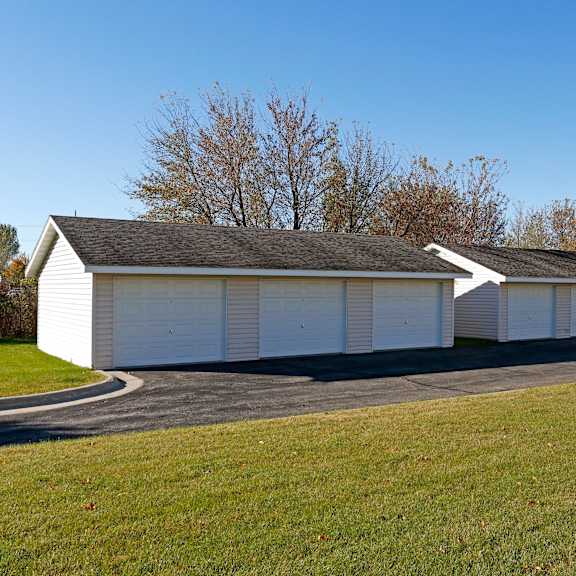 a long white garage with a black roof and a white car parked in front.