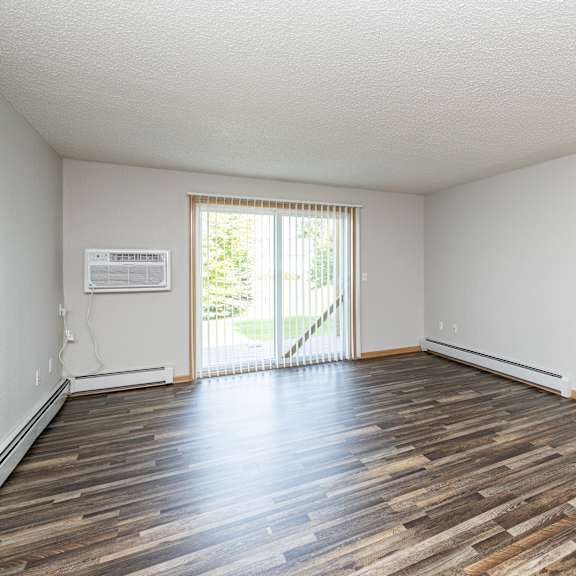 a room with wooden flooring and a sliding glass door leading outside.