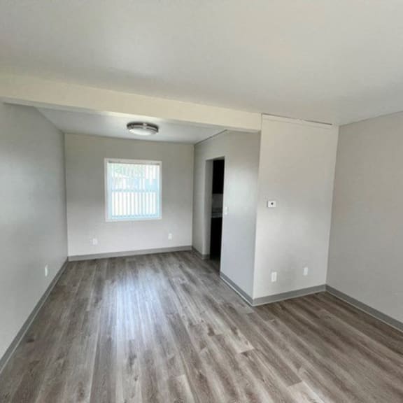 an empty living room with wood floors and a window