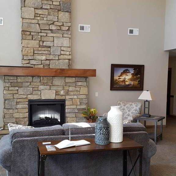 a living room with a stone fireplace and grey couches.