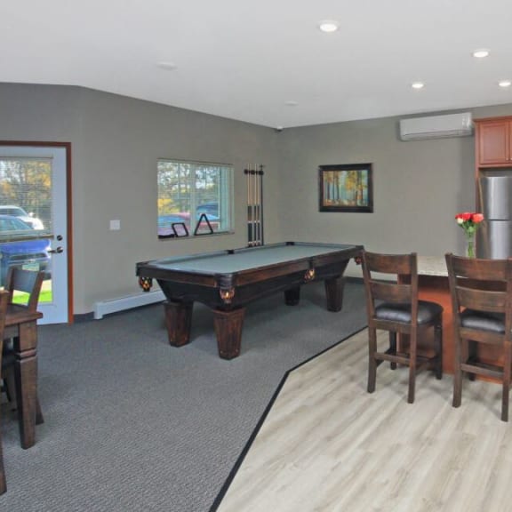 a living room with a pool table and a kitchen