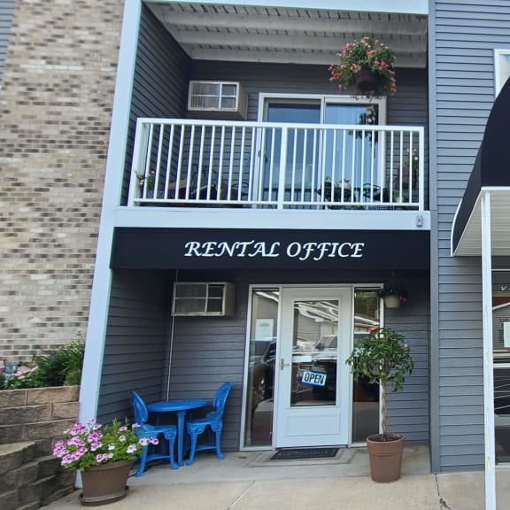 the front of a grey apartment building with a blue awning and a door
