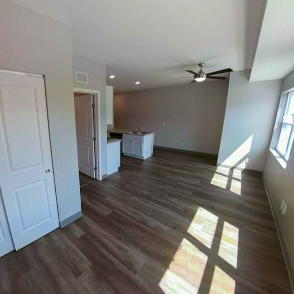 an empty living room with wooden floors and a ceiling fan
