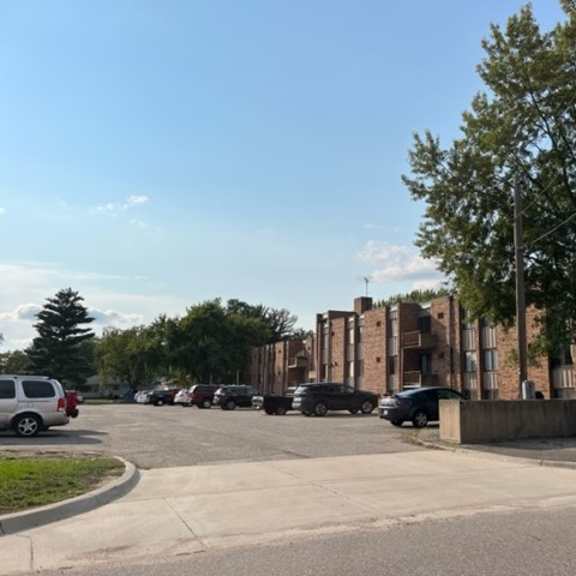 a parking lot with cars and a building in the background.