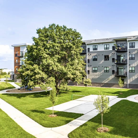 an exterior view of golden aspen flats with a pickle ball court, picnic area, grass and trees