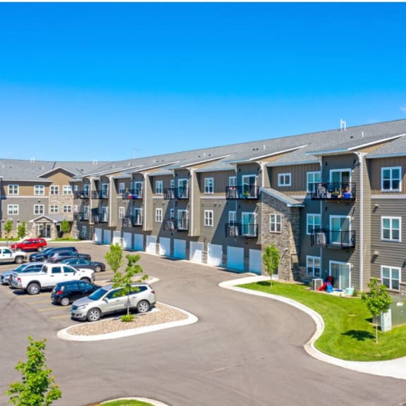 an exterior view of an apartment building with cars parked in a parking lot