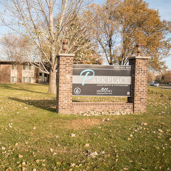 a sign for park place apartments is in front of some buildings.