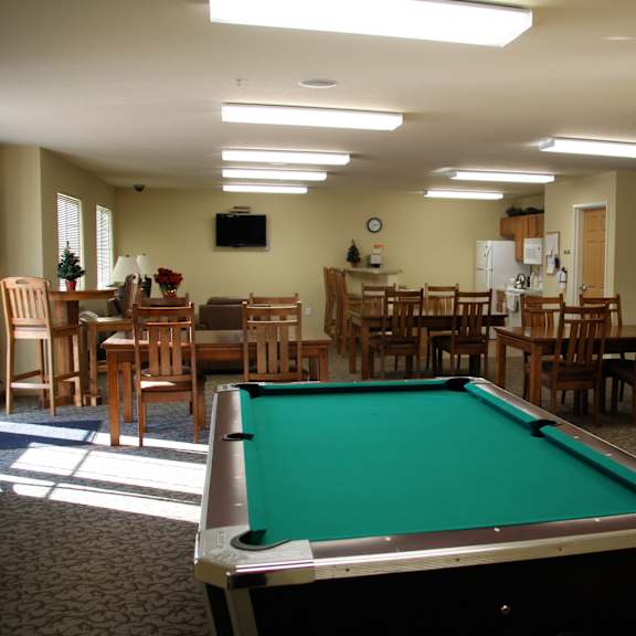 a pool table is in the middle of a room with chairs and tables.