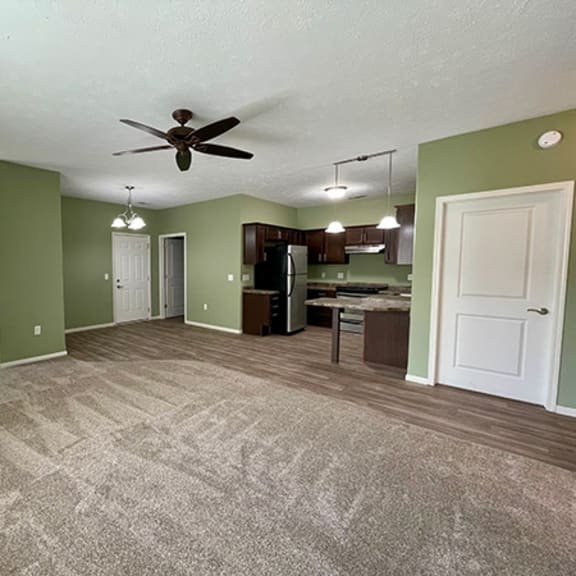 an empty living room and kitchen with a ceiling fan