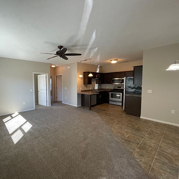 an empty living room and kitchen with a ceiling fan