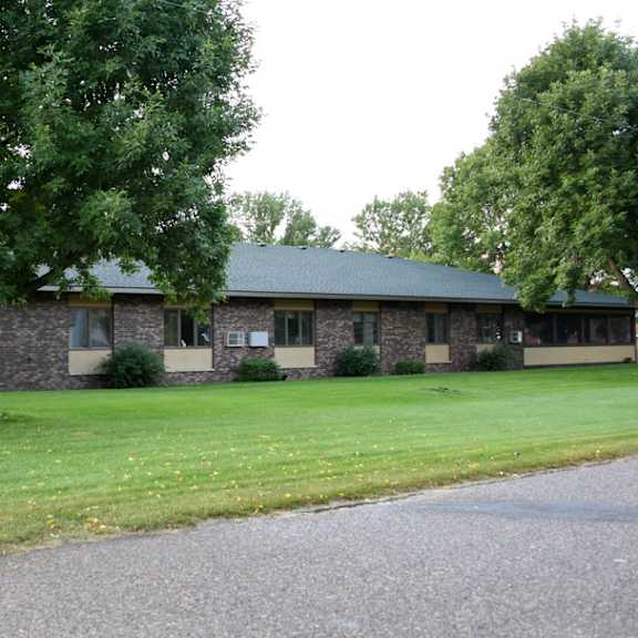 a building with a green roof and a tree in front of it.