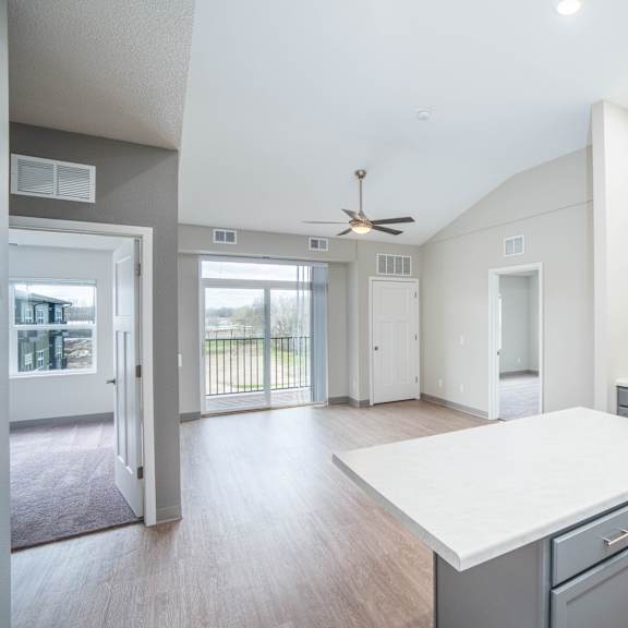 an open kitchen and living room with an island and a ceiling fan