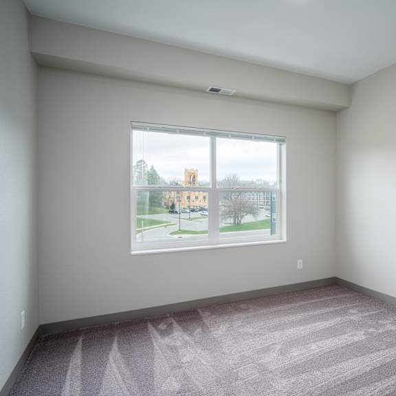 an empty room with a large window and carpeting
