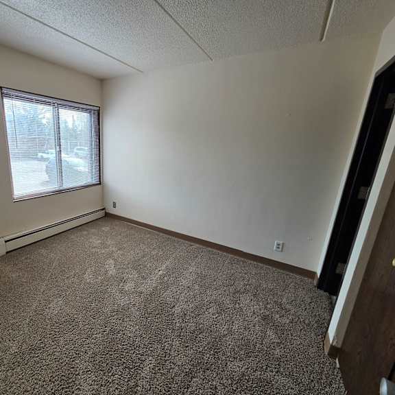 a room with a carpeted floor and a window with blinds.