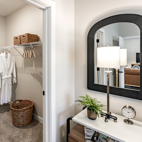 a hallway with a mirror and a closet with a white robe and a dresser